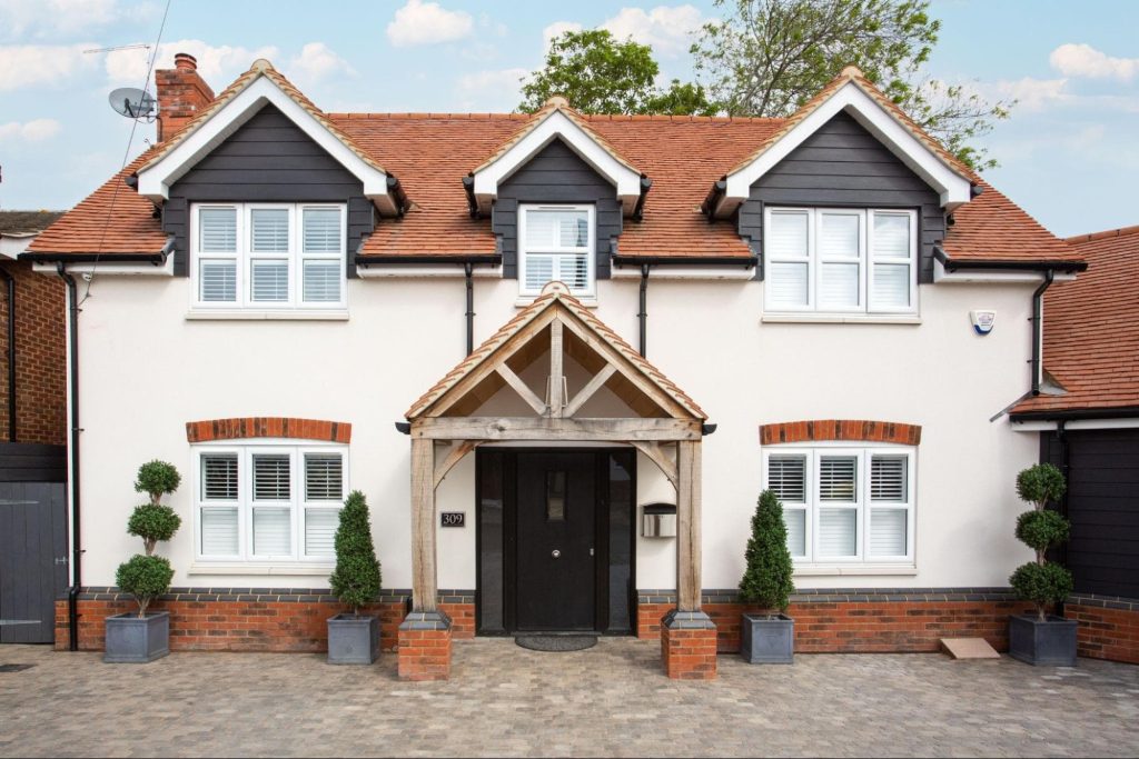 Two-storey house with a black and white exterior, red-tiled roof, symmetrical windows, front porch with wooden beams, and potted plants by the entrance—perfect for your 2026 housebuilding visualisation or 3D rendering pricing project.